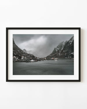 Reine waterfront beneath storm clouds and snow-streaked Norwegian mountains