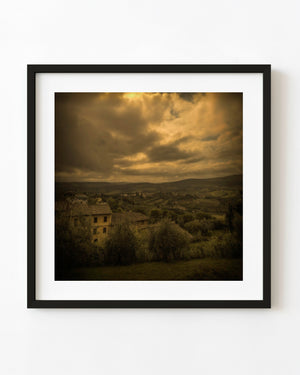 Tuscany farmhouse and rolling countryside beneath golden storm clouds