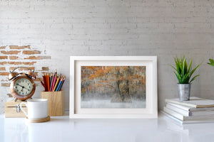Framed abstract art piece on a desk with stationery items and decor.