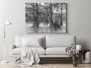 Living room with a white sofa, lamp, and decorative items, featuring a large wall art of a forest scene.