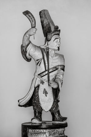 Figura de escultura de templo tradicional japonés sosteniendo espada en Fotografía monocromática