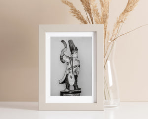 Fotografía en blanco y negro de la tradicional estatua del guardián con túnica estampada y botas