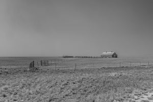 Nebraska prairie barn beyond fences and open grassland