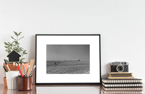 Black and white view of a distant barn and fenced prairie pasture