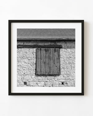 Weathered wooden shutters on a Nebraska stone barn in black and white