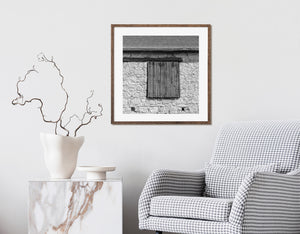 Rustic stone barn wall and dark timber shutters in monochrome
