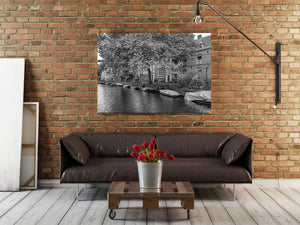 Quiet canal street in Amsterdam with boats and leafy trees black and white