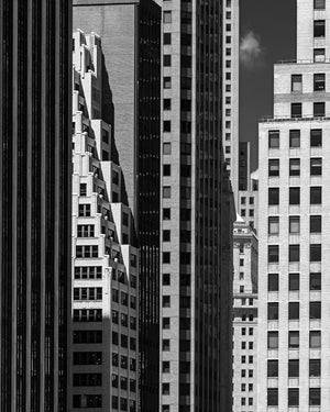 Dense New York City architecture with bright stone facades and dark high-rise buildings.