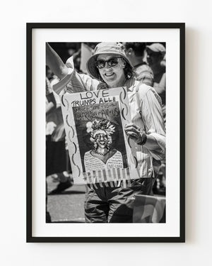New York Pride marcher with a raised arm and handmade sign in black and white
