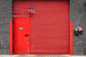 Bright red industrial doorway set into dark New York brickwork