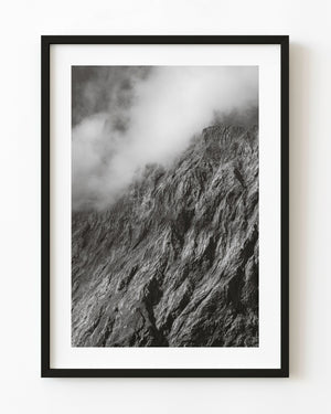 Mist drifting across a rugged New Zealand mountain face in black and white