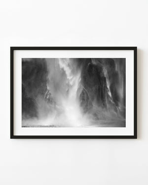 New Zealand waterfall spray descending over a dark cliff in black and white