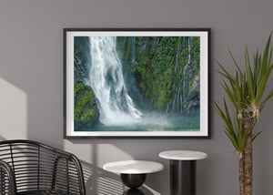 Mist-filled waterfall flowing over vertical rock wall in New Zealand