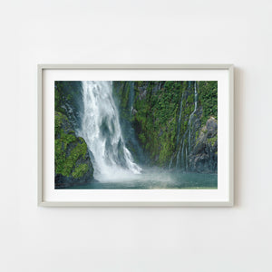 Waterfall cascading down steep rock face in Milford Sound New Zealand