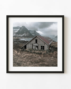 Weathered wooden boathouse on the Lofoten coast beneath snowy mountains