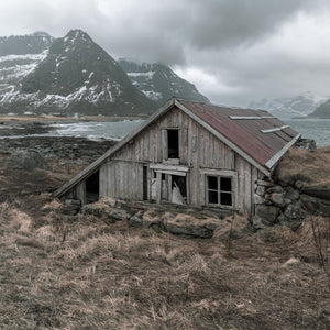 Rustic Norwegian boathouse with a rust-red roof beside the sea