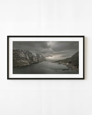 Norwegian fjord opening toward the ocean beneath heavy clouds