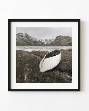 White rowboat resting beside a frozen Norwegian mountain lake
