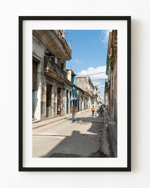 Pedestrians walking beneath weathered balconies in Old Havana