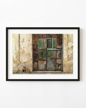 Weathered garage doors with peeling green panels in Old Havana