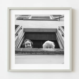 Elderly women laughing at window during Tuscan festival