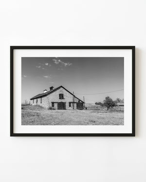 Old Nebraska stone barn standing in open country in black and white