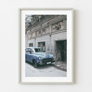 Blue classic Pontiac parked beside rustic Havana building