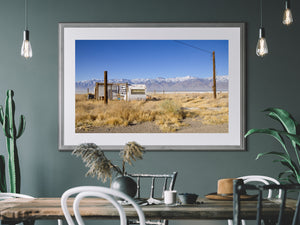 Blue sky and distant snowy peaks above a small weathered caravan