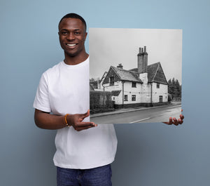 Man holding a black and white photo of a house against a blue background