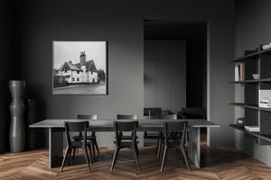 Modern dining room with a large table and chairs, framed black and white photo on wall, and bookshelf.