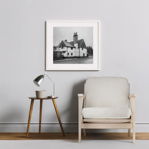 Framed black and white photograph on a wall above a chair and side table.