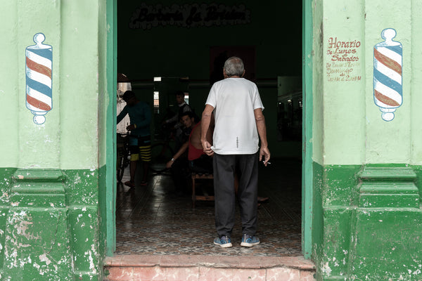 Local men sitting in dark interior of Cuban barber shop