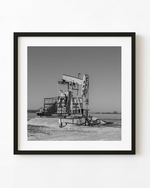 Oil pumpjack standing in open Ontario farmland, black and white