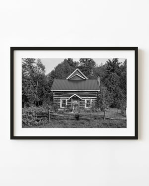 Black and white photograph of a historic Ontario log cabin surrounded by forest
