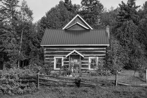 Rustic log farmhouse with split rail fence in rural Ontario black and white