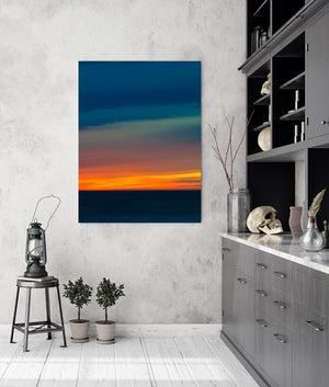 Dark ocean beneath layered blue and orange evening sky