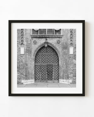 Ornate Gothic doors beneath a pointed brick arch at St Mary’s in Gdansk, black and white