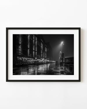 Wet paving reflecting restaurant lights at Oslo’s Aker Brygge on a foggy night