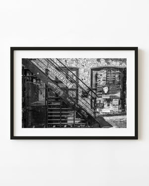 Iron stairs crossing a graffiti-covered Oslo wall with concert posters, black and white