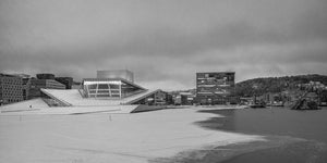 Snow-covered Oslo Opera House and Munch Museum across frozen harbour water