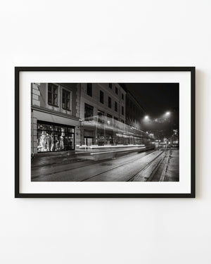 Oslo tram leaving light trails along a wet street at night, black and white