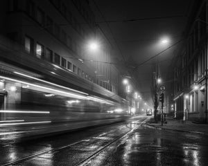 Blurred streetcar passing wet Oslo tram tracks beneath glowing lamps