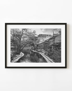 Winter riverside scene in Oslo with graffiti-covered buildings and bare trees, black and white