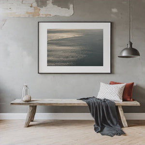 Muted blue-grey ocean surface covered in delicate sunlit ripples