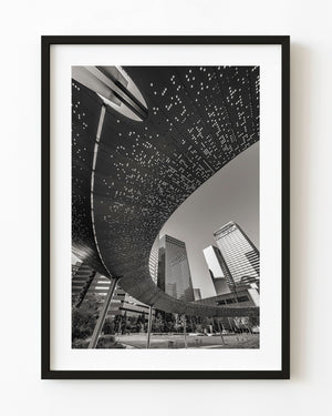 Perforated Pacific Plaza canopy curving above Dallas towers, black and white
