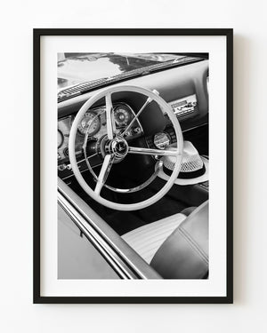 Pale steering wheel and summer hat inside a classic car, black and white