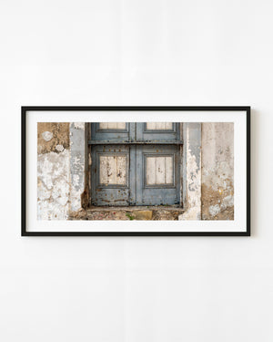Weathered blue-grey wooden door surrounded by peeling plaster in Panama City