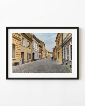 Pastel facades lining a cobblestone street in Brașov, Romania