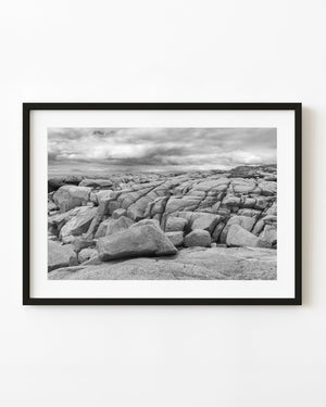 Granite rocks beneath layered clouds at Peggy’s Cove, black and white