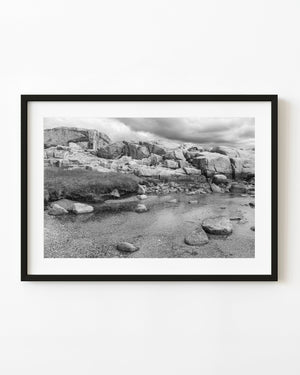 Granite shore and shallow tidal water at Peggy’s Cove, black and white